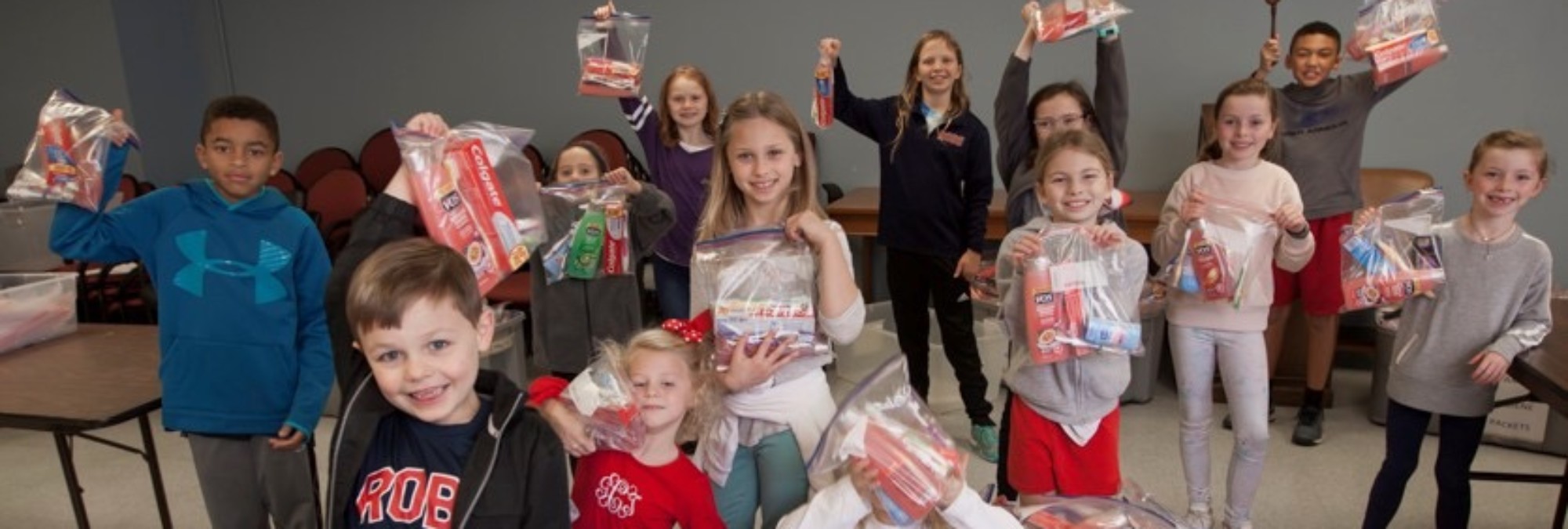 A group of children holding up bags of toiletries