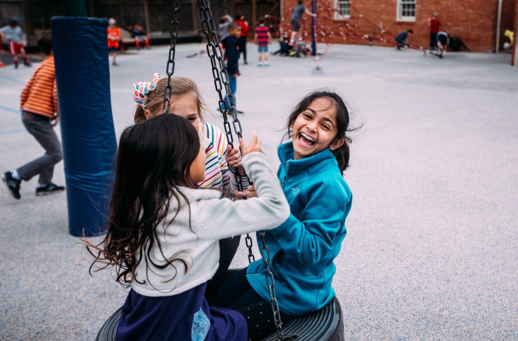A group of girls on a swing in a playground of River Oaks Baptist School