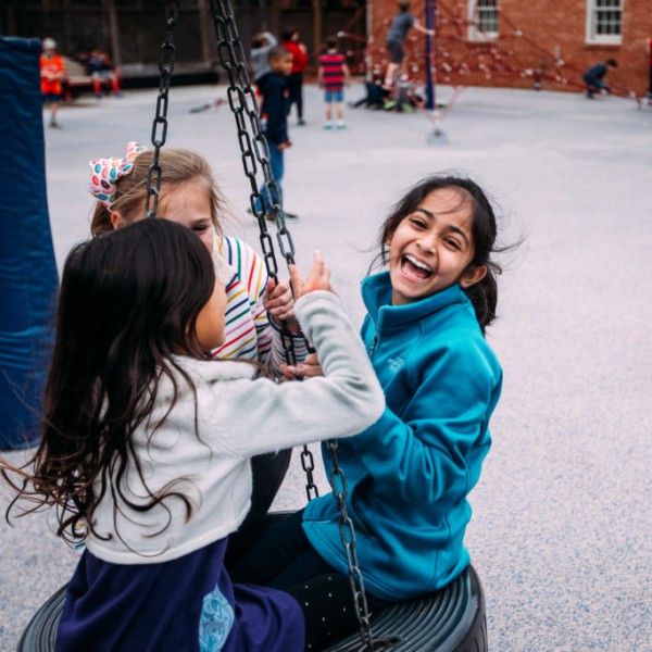 A group of girls on a swing in a playground of River Oaks Baptist School