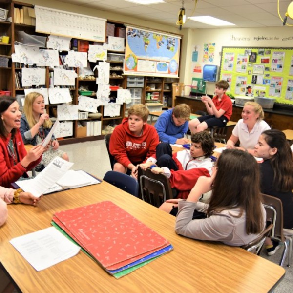 A teacher with students sitting around a table in a classroom at River Oaks Baptist School