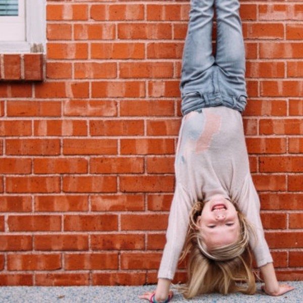 A girl hanging upside down on a brick wall