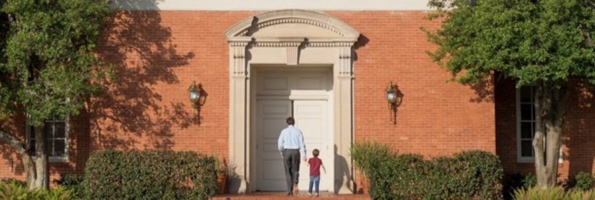 A father and a little kid standing in front of a building