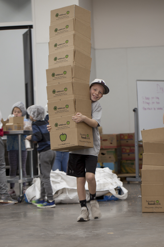 A young boy carrying a large stack of boxes