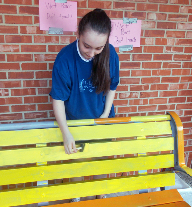 A young woman standing next to a yellow bench at River Oaks Baptist School