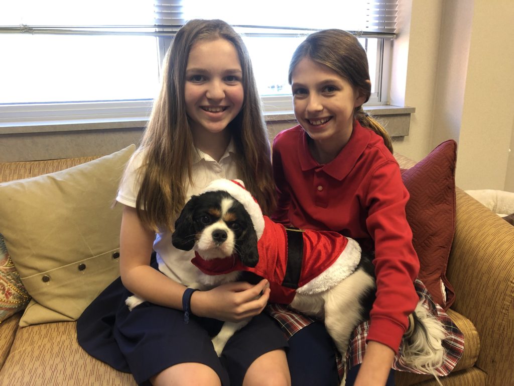 Two girls students sitting on a couch with a dog at River Oaks Baptist School