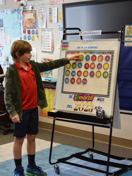 A young boy standing in front of a whiteboard in a classroom