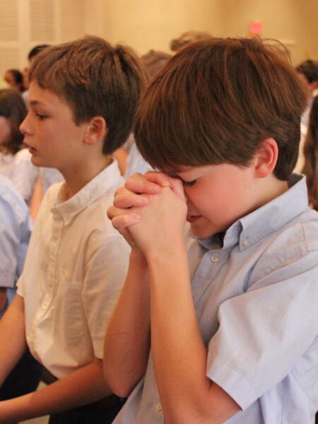 A group of young children sitting doing prayer at River Oaks Baptist School
