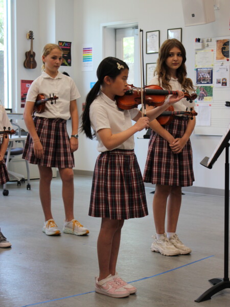 A group of girls in school uniforms playing violin at River Oaks Baptist School