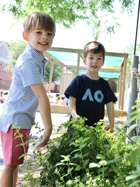 Two young boys standing next to each other in a garden at River Oaks Baptist School