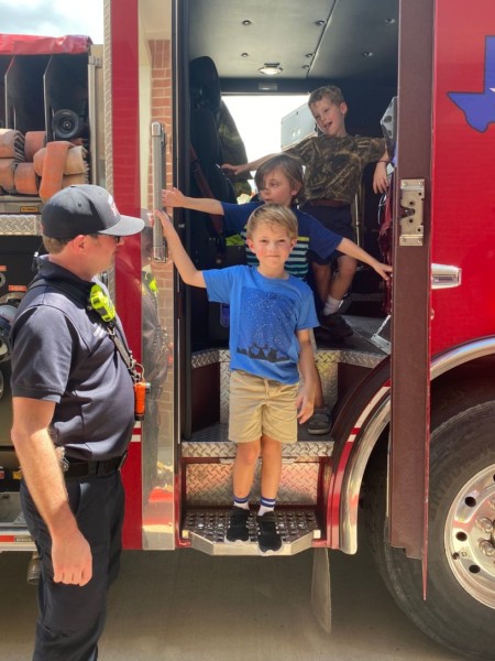 A man standing next to a boy in a fire truck