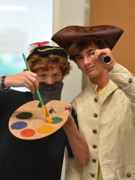 Two people dressed up in costumes holding paintbrushes and palettes at River Oaks Baptist School