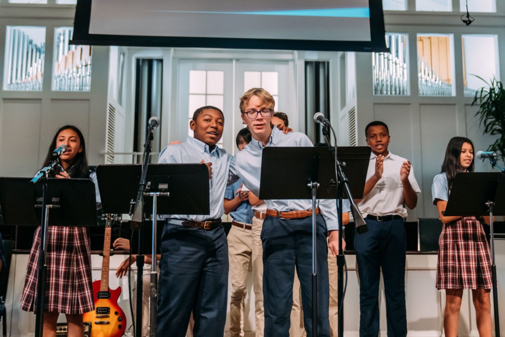 A group of students singing on stage at River Oaks Baptist School