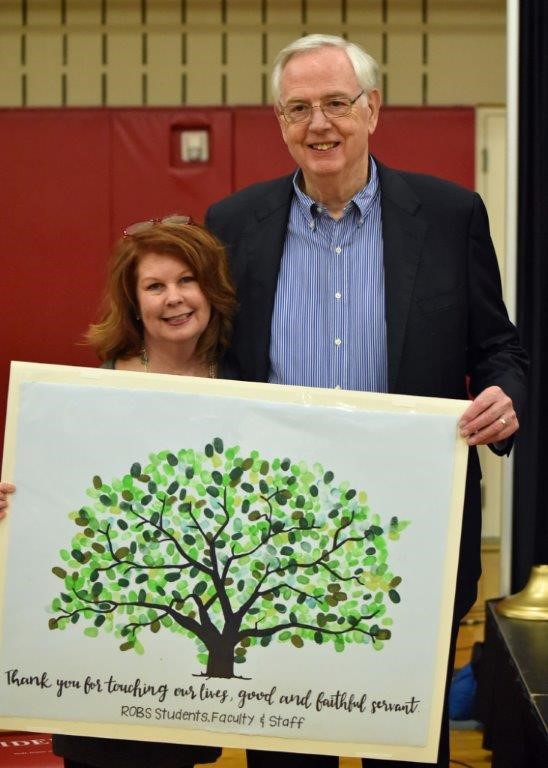A man and a woman holding a painting of a tree