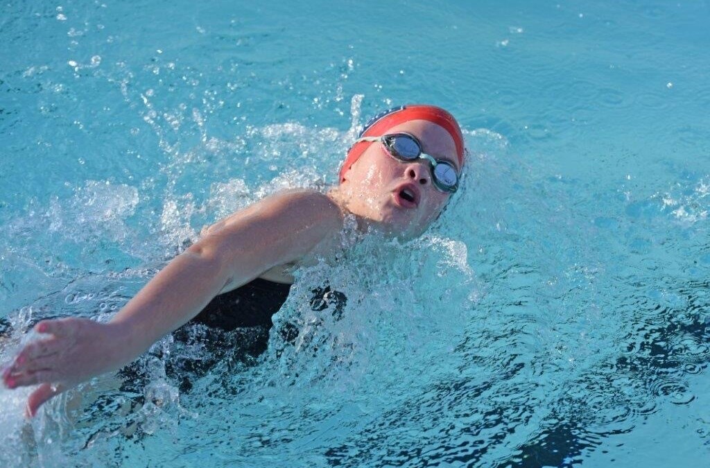 A person swimming in a pool with goggles on
