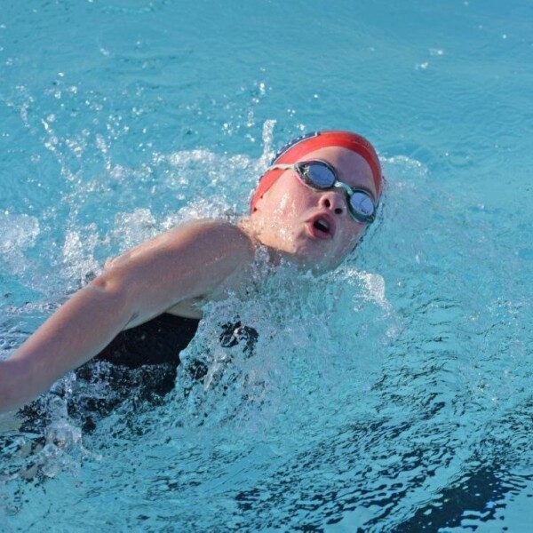 A person swimming in a pool with goggles on