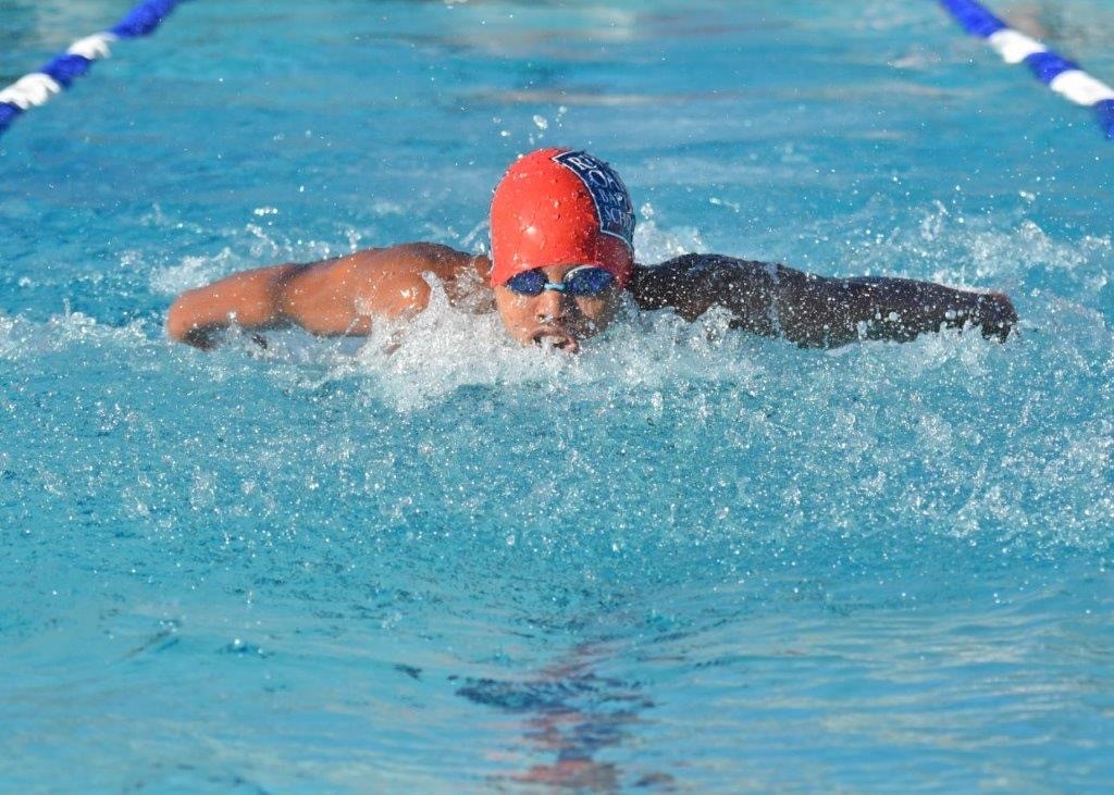 A ROBS student swimming in a pool with a red cap