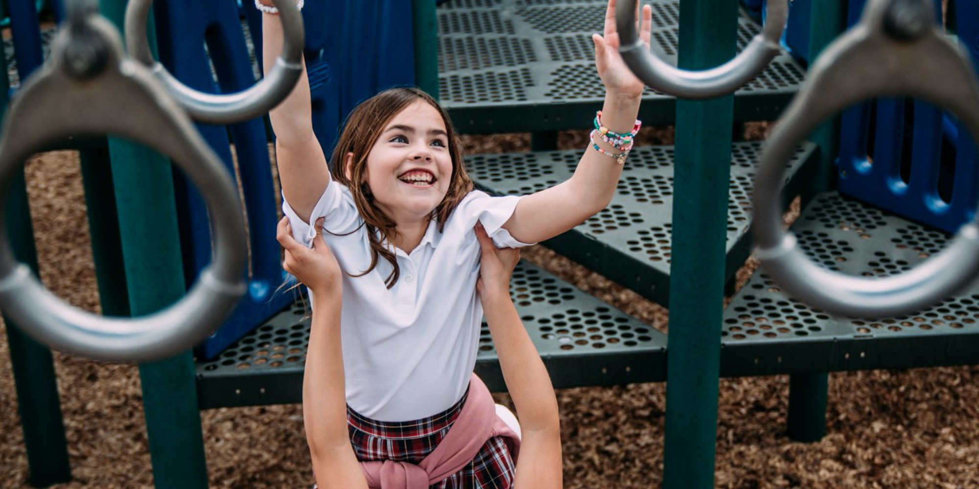 A young girl is playing on playground equipment at River Oaks Baptist School