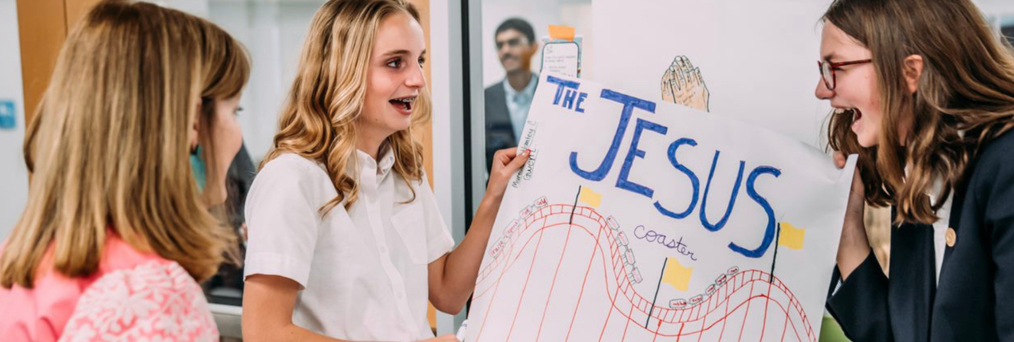 A group of girls students standing around a signboard "The Jesus" at River Oaks Baptist School