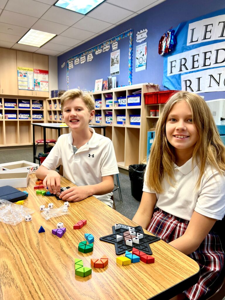 Two students sitting at a table with Legos in a classroom