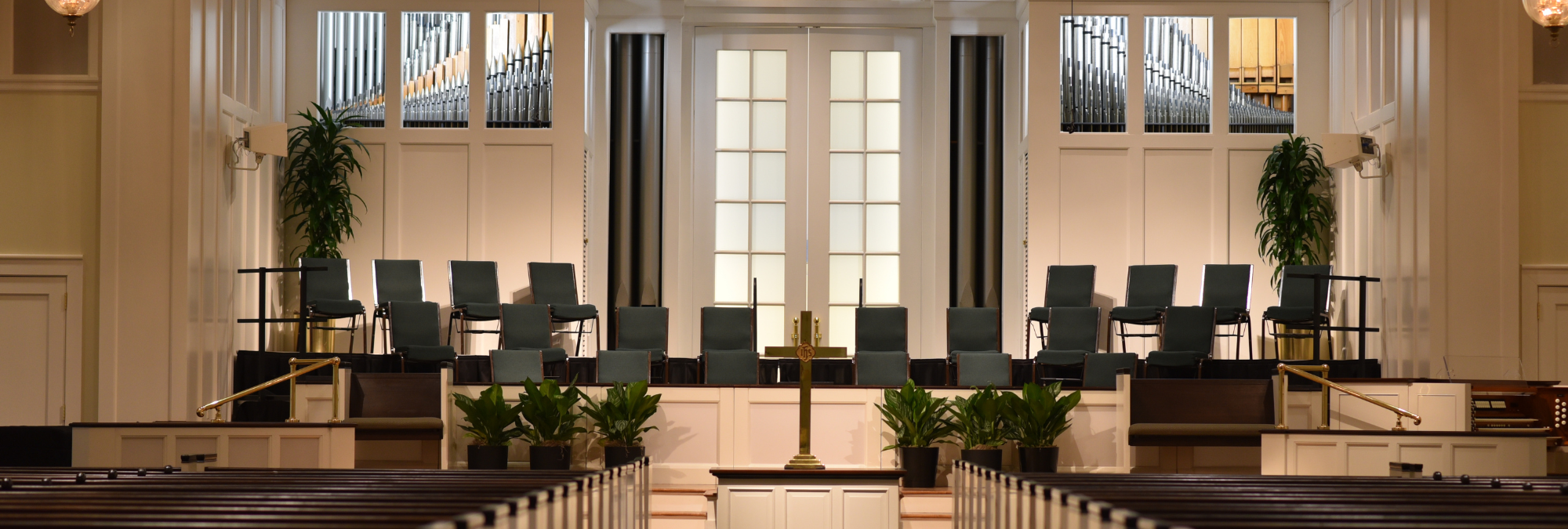 An empty church with pews and a cross at River Oaks Baptist School